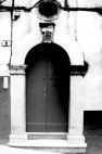 Fig. 35 Via Custoza 2. Portale ad arco a tutto sesto con stemma in chiave d'arco a protiride decorato con elementi a bassorilievo; con imposte dei piedritti a capitello e basi rimarcate ed è sovrastato da una finestrella di forma circolare. Particolare: Stemma in chiave d'arco a protiride con decorazioni a bassorilievo.