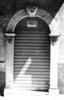 Fig. 38 Corso Matteotti 33. Portale ad arco a tutto sesto con stemma in chiave d'arco, raffigurante a bassorilievo una testa di leone; con imposte dei piedritti a capitello a basi rimarcate. Particolare: Stemma in chiave d'arco raffigurante in rilievo la testa di un leone..